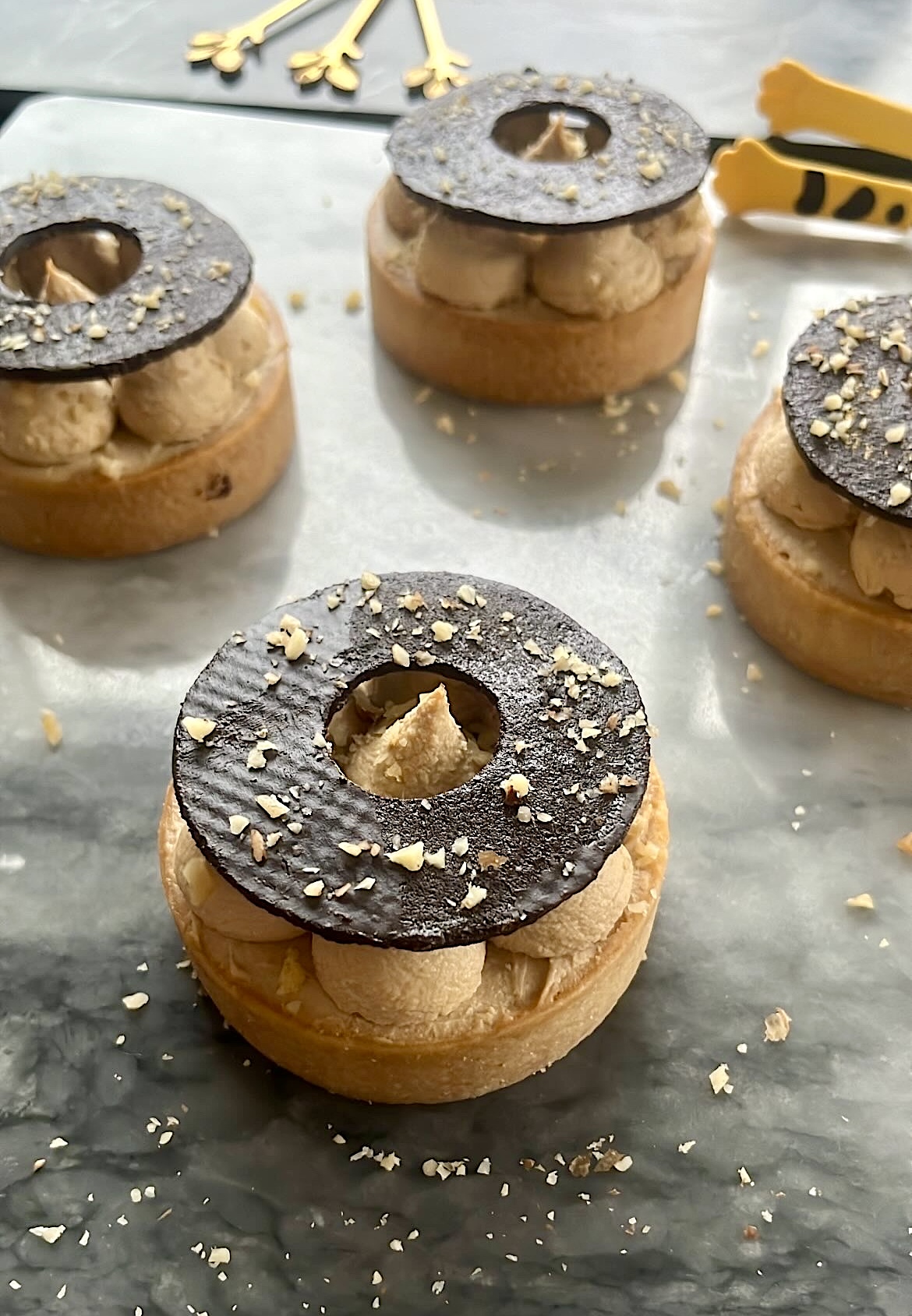 A tart decorated with coffee cream and topped with a ring-shaped chocolate